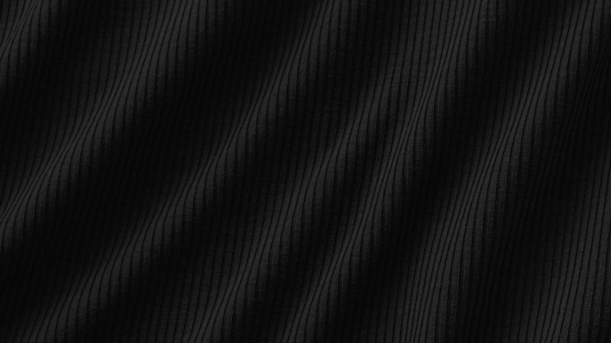 A close-up of a black ribbed fabric texture with a fine vertical stripe pattern and soft diagonal folds.