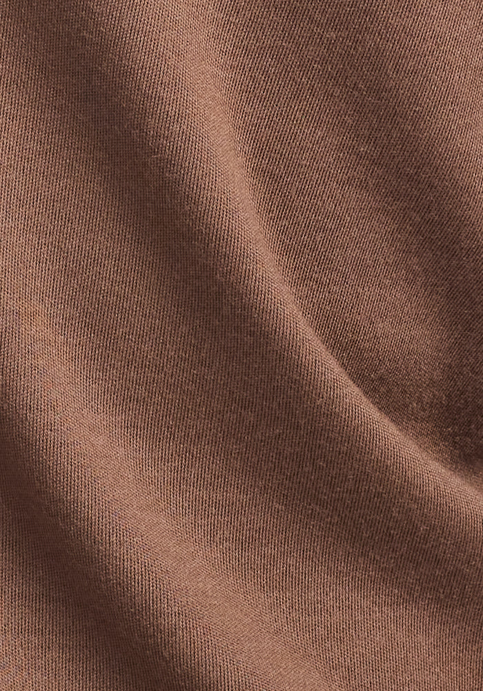 Close-up of the Woolx Grizzly Sweatshirt in Bourbon Oak, showing its brown ribbed Merino wool, soft folds, and gentle shadows that emphasize the textured weave and moisture-wicking qualities.