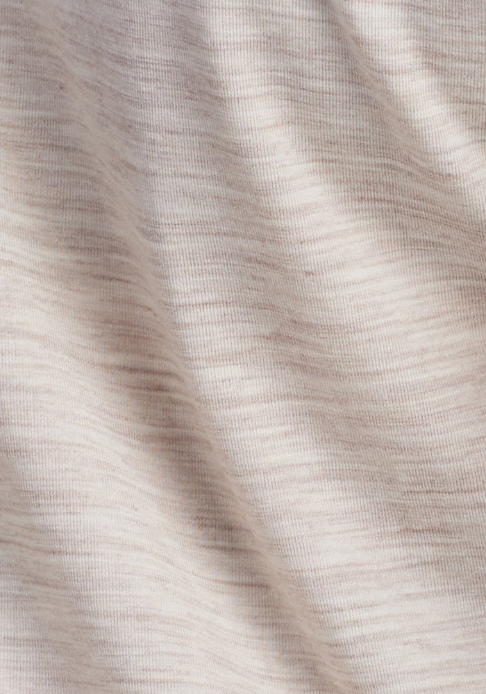 Close-up of the Woolx Hazel Tunic - Cream Heather, showcasing its light beige, temperature-regulating merino wool fabric with subtle horizontal stripes and soft shadows that highlight the texture and gentle folds.