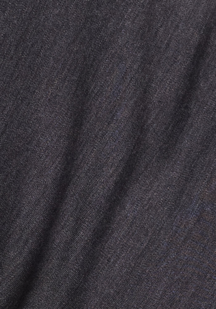 Close-up of the Woolx Hannah Long Sleeve Top in Cinder Melange, showing its dark gray merino wool fabric with a soft, textured surface and gentle diagonal creases that highlight excellent moisture-wicking properties.