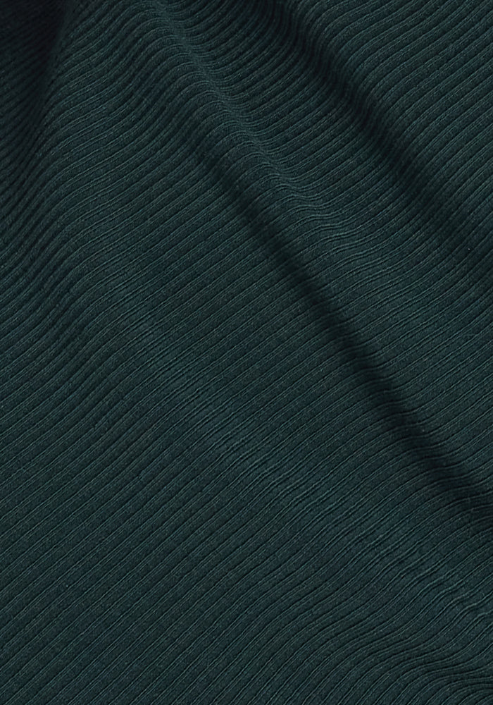 Close-up of the Woolx Ainsley Sweater in Deep Timber, featuring a dark green ribbed texture with gentle folds that form subtle shadows and highlights.