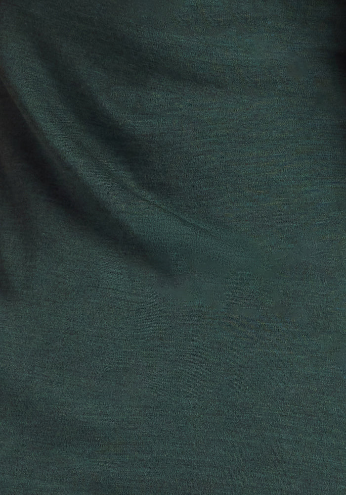 Close-up of the Woolx Hannah Long Sleeve Top in Forest, featuring dark green, odor-resistant Merino wool fabric with a soft texture and subtle folds, creating gentle shadows and highlights across the surface.