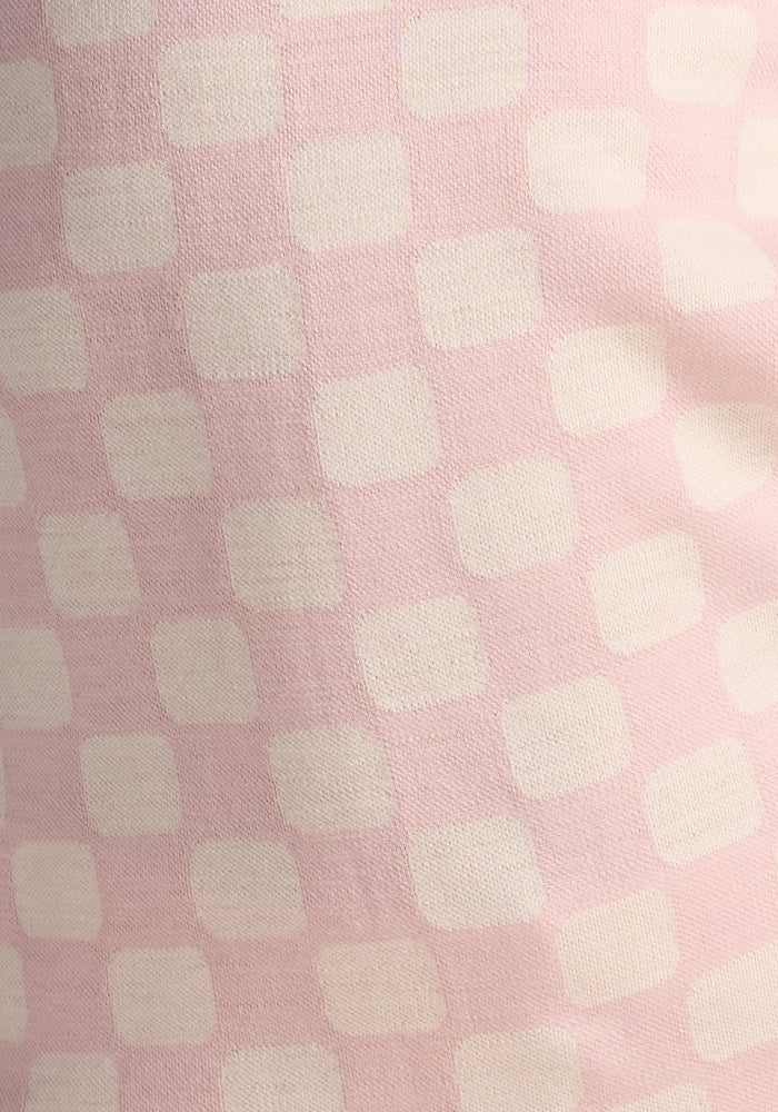 Close-up of the Woolx Kids Explorer Base Layer Top in Hopscotch Pink, showing soft, moisture-wicking Australian Merino wool with off-white rounded squares in a checkerboard pattern and a slightly textured finish.