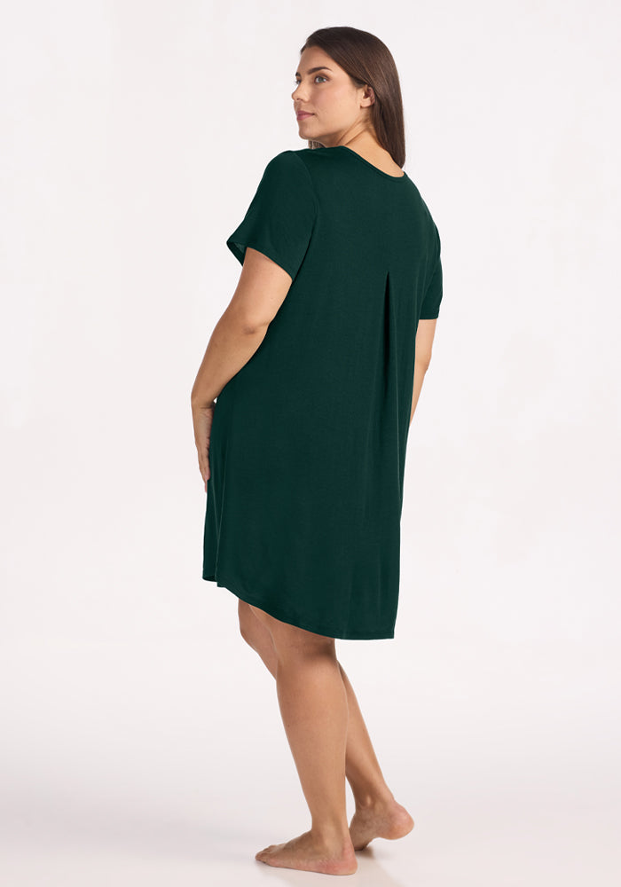 Back view of a woman in a dark green, short-sleeved Desi Nightgown - Deep Pine with a pleated back panel.