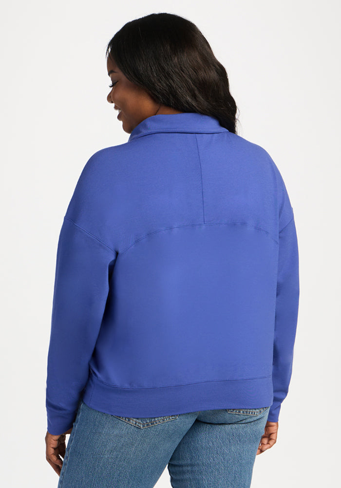 A person seen from behind wearing a royal blue Woolx Tori 1/4 Zip lightweight merino pullover.