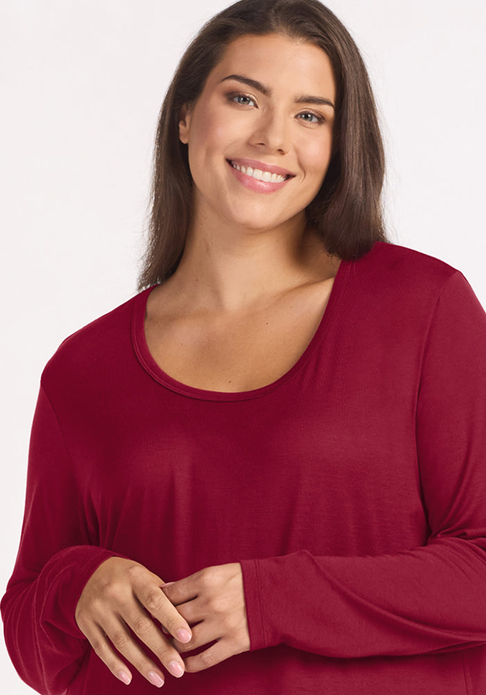 A smiling woman wearing a beet red Woolx Lucille Long Sleeve Nightgown.
