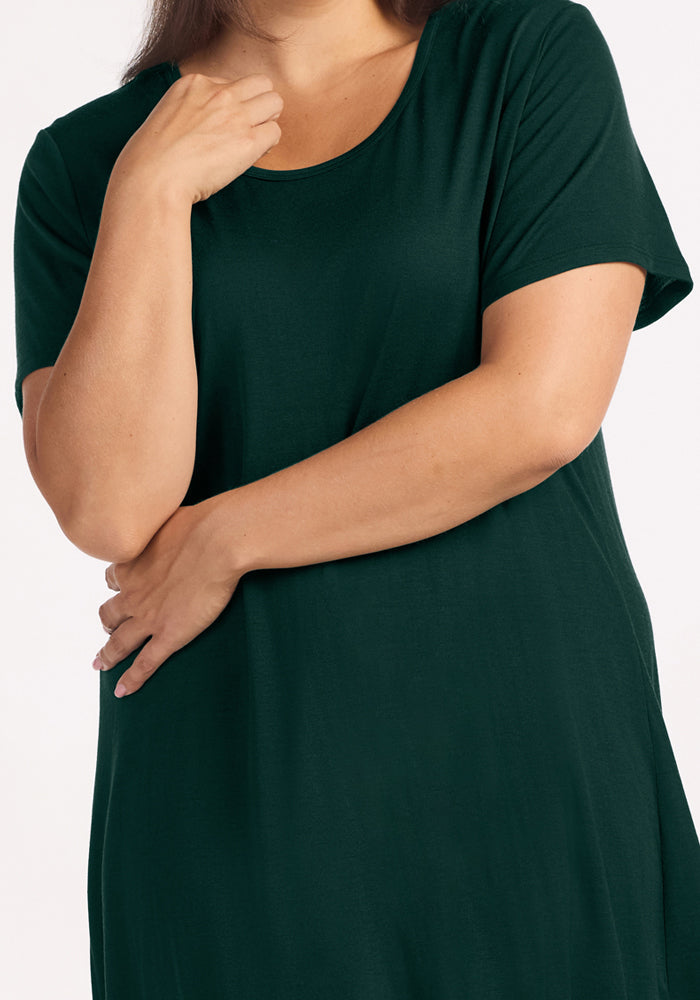 A person wearing a short-sleeved deep pine Woolx Desi Nightgown made of moisture-wicking fabric.