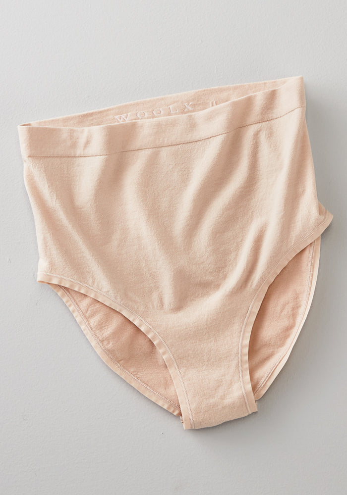 The Woolx Mabel Full Coverage Underwear in Sand, a seamless high-waisted cotton brief, lies flat to display its front and waistband with subtle branding along the top.