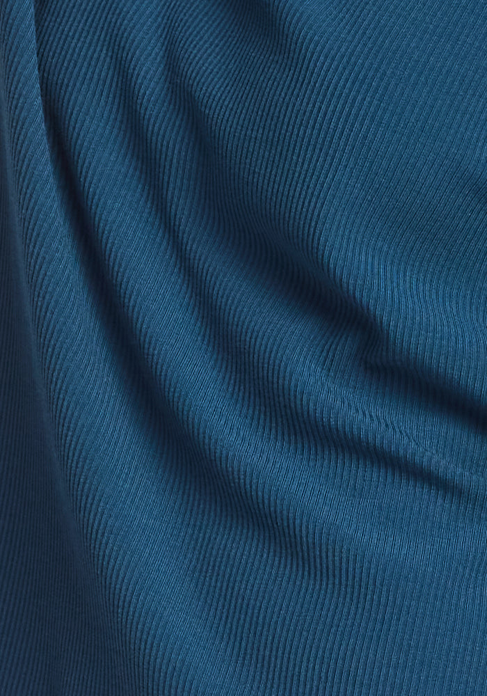 Close-up of the blue ribbed fabric on the Woolx Ainsley Sweater in Majolica Blue, showing textured lines and gentle folds that create a pattern of shadows and highlights.