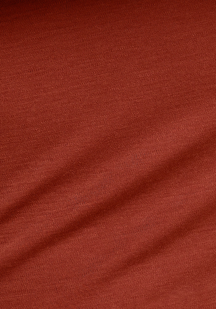 Close-up of the Woolx Blair Tunic in Maple Leaf shows its fine wool texture, soft surface, and gentle horizontal creases, highlighting the sweater’s smooth appearance and quality weave.