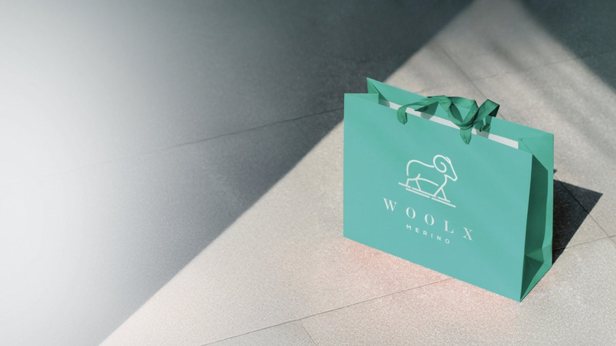 Teal shopping bag with 'WOOLX' logo on a light gray floor