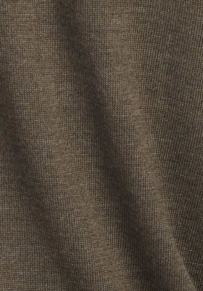 Close-up of the Woolx Collins Half Zip Sweater in Pine Needle, highlighting its ribbed texture and natural drape that showcases the sweater’s flexible Merino wool fabric. Soft shadows and subtle folds enhance its cozy appeal.