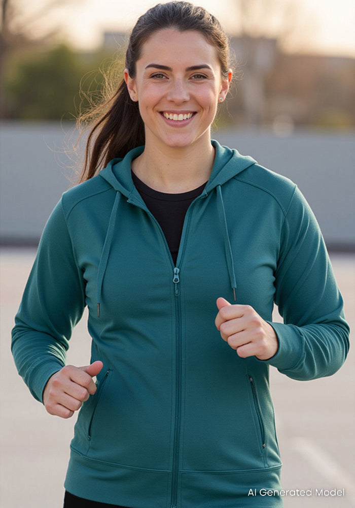 A woman wearing the Woolx Ryann Hoodie in Tidepool is smiling and jogging outdoors on a sunny day.