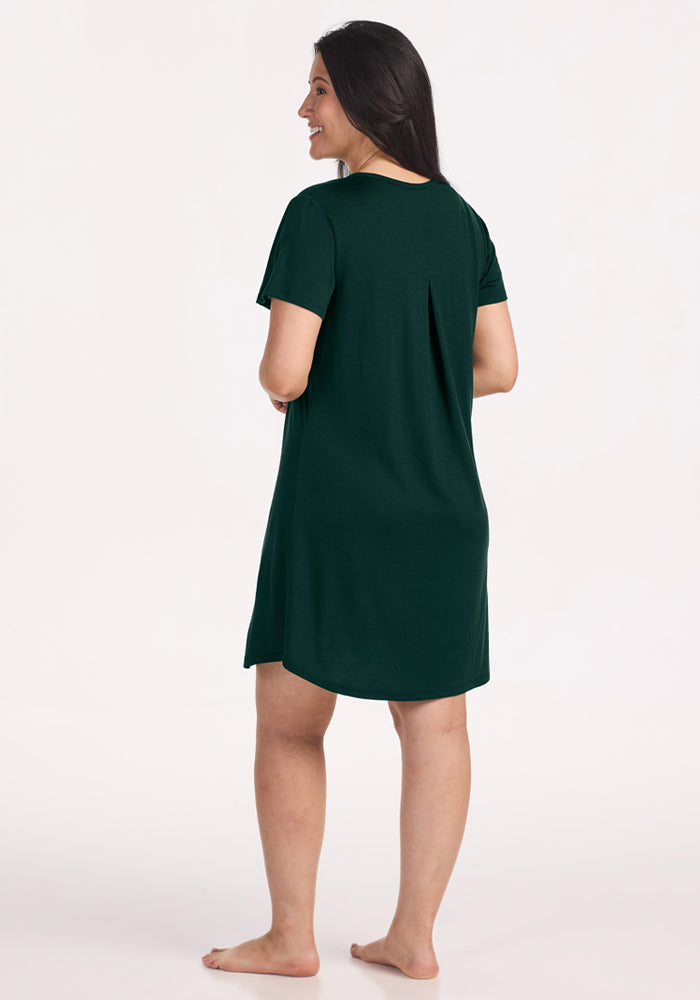 A woman seen from behind wearing a pleated, deep pine Woolx Desi Nightgown made of Merino wool.