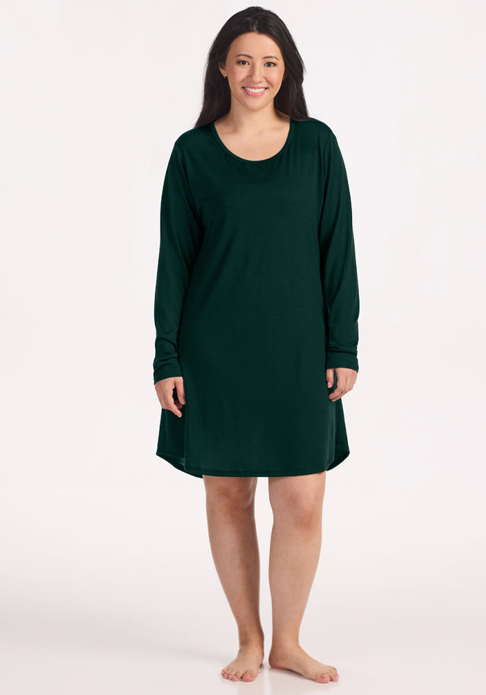 A woman wearing a dark green long-sleeve Woolx Lucille Long Sleeve Nightgown - Deep Pine.