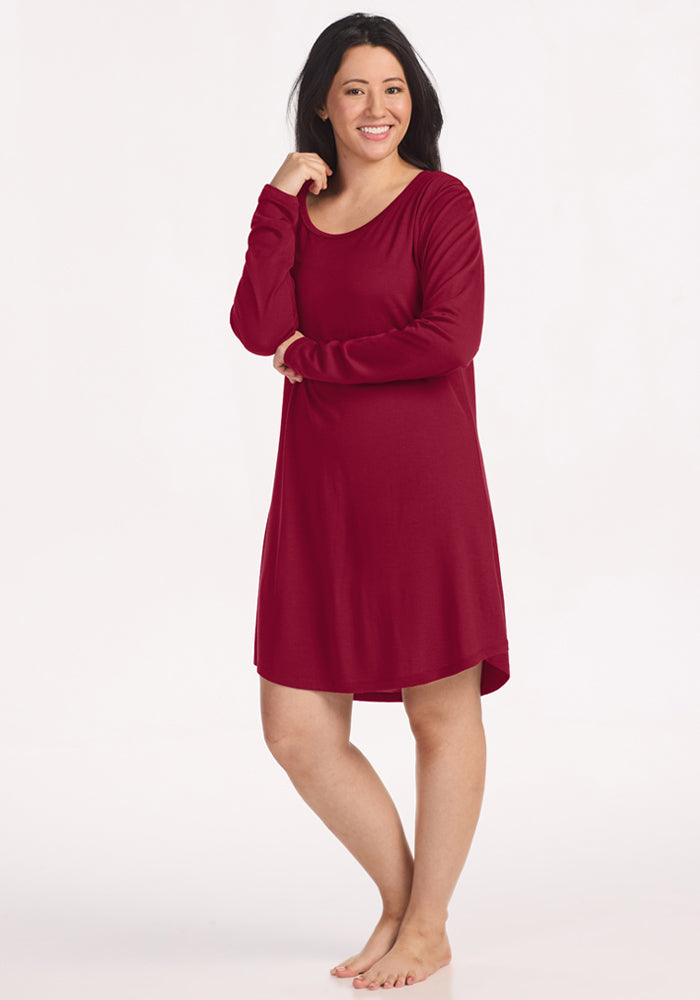 A woman smiles wearing a beet red Lucille Long Sleeve Nightgown with long sleeves and a scoop neckline. 