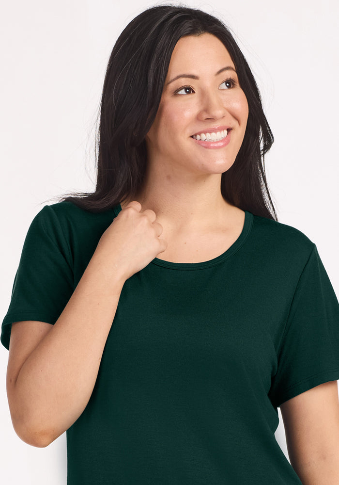 A woman wearing a Woolx Desi Nightgown - Deep Pine, a moisture-wicking, dark green, short-sleeved crewneck nightgown.