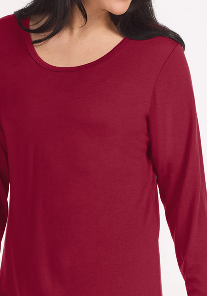 A person wearing a beet red Woolx Lucille Long Sleeve Nightgown with a scoop neck.