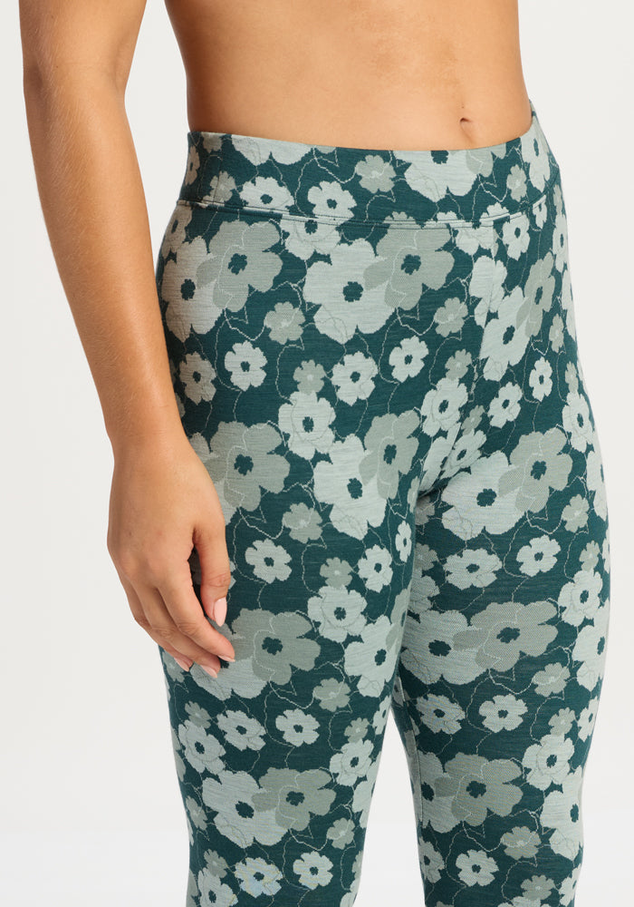 Model wearing Woolx Taylor Baselayer Leggings - Coastal Wildflower, high-waisted, teal with a blue floral design.