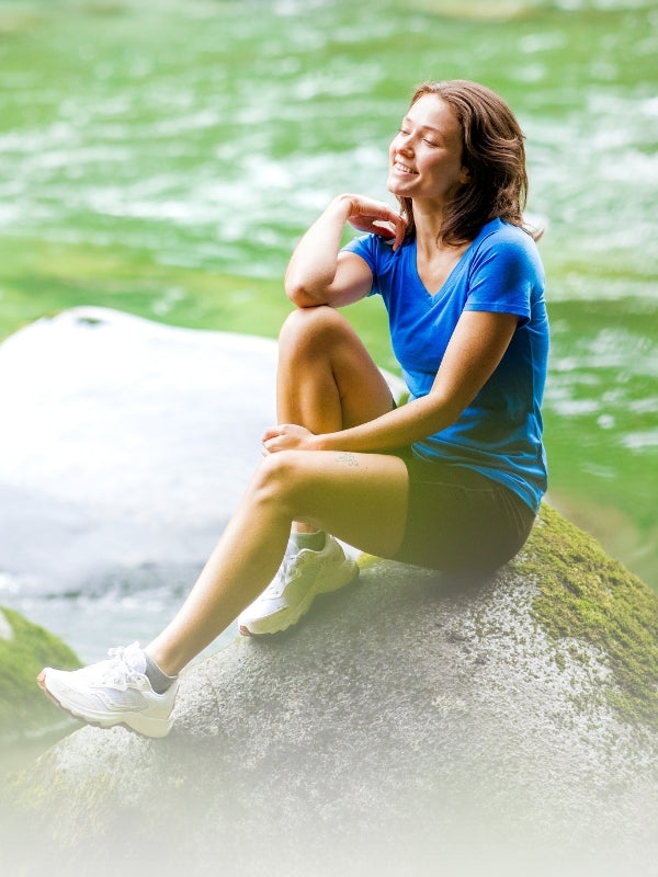 Woman sitting on a rock by a flowing river