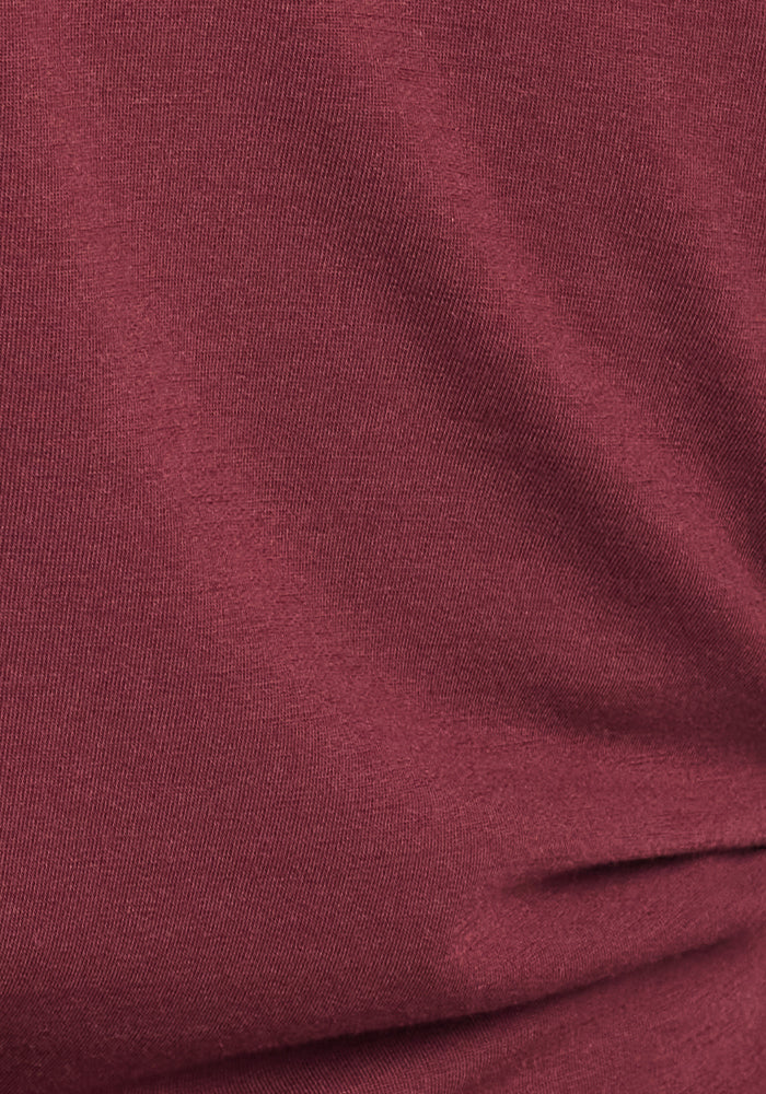 Close-up of the Woolx Stella Leggings in Toasted Garnet shows smooth, maroon fabric with soft folds and gentle shadows, highlighting their warmth and plush texture—perfect for cozy winter layering.