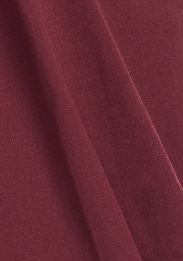 Close-up of the Rissa A Line Dress in Toasted Garnet by Woolx, featuring maroon fabric with soft folds and a smooth texture. This evenly colored material drapes gently, ideal for fall and winter wear.
