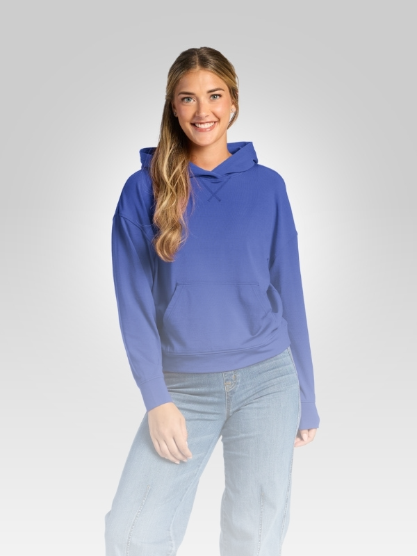 Smiling model wearing the Lizzy Hoodie in bright blue with light-wash jeans against a light gray background.