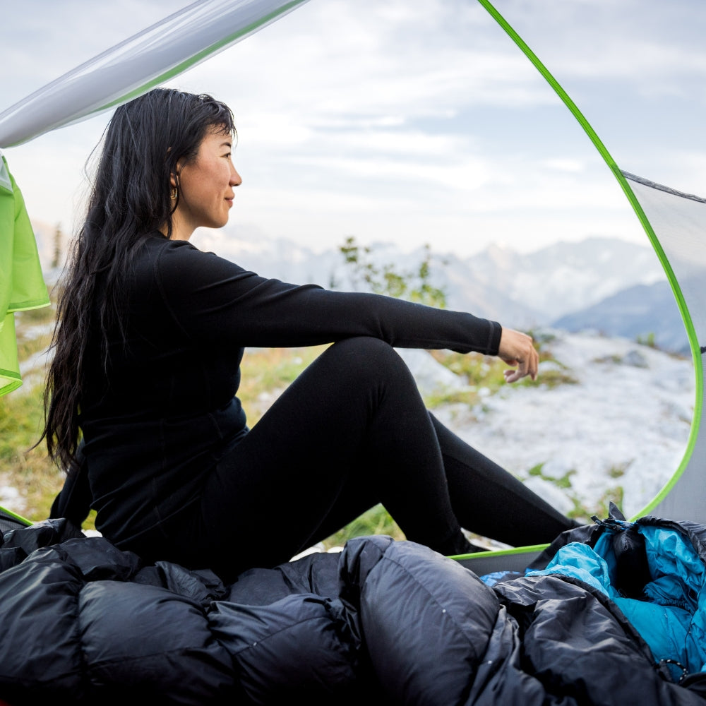 Woman in black top and leggings sitting inside a tent