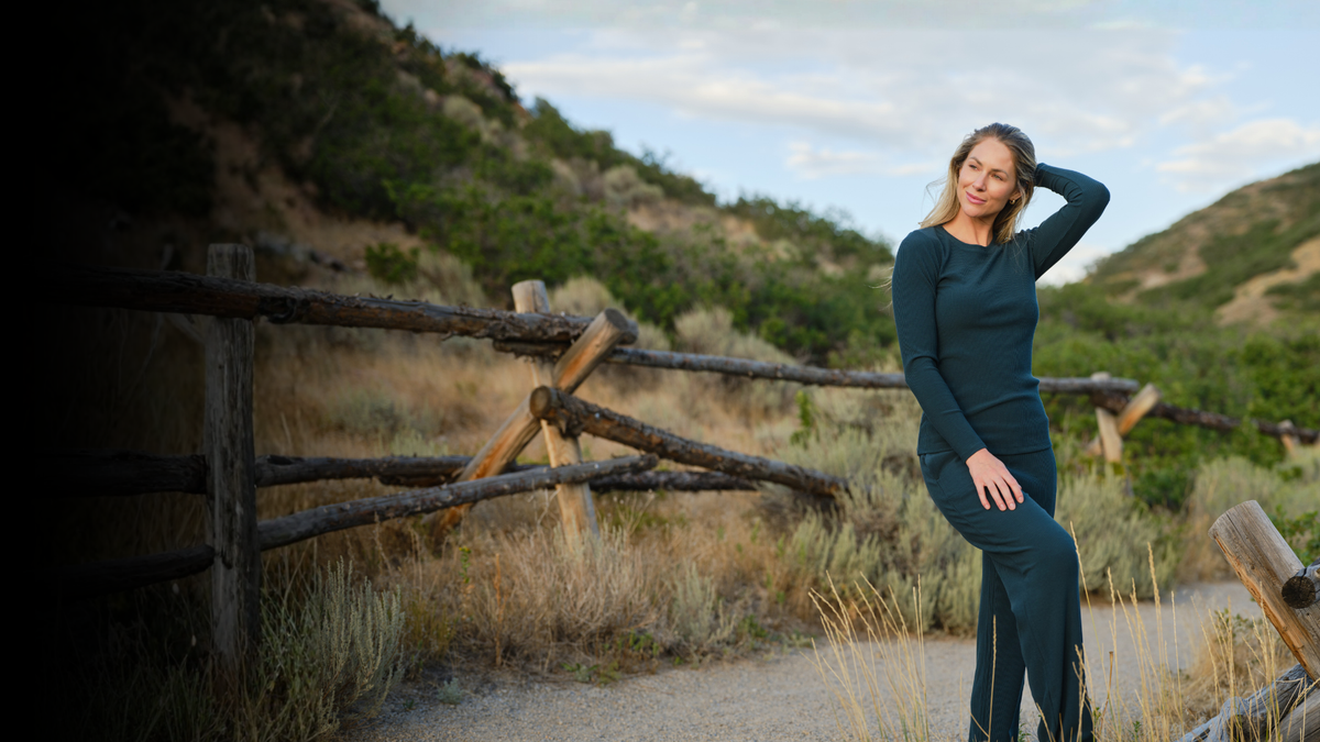 Woman standing on a rocky trail wearing green leggings and a green long sleeved shirt. 