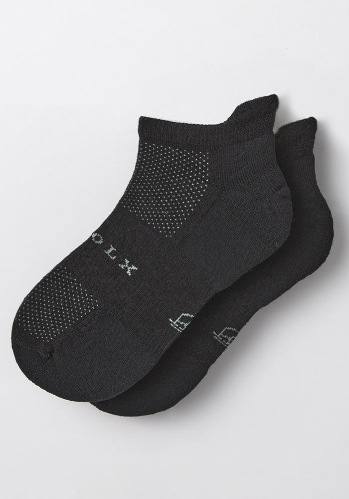 The Mens Rowan No Show Socks in Black Pepper by Woolx feature a black cushioned design with white dotted patterns and subtle white text, displayed on a plain white background.