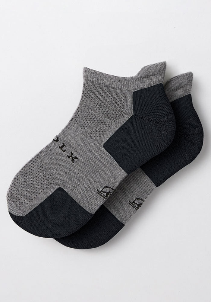 The Womens Rowan No Show Socks - Pebble by Woolx feature cushioned gray and black design, reinforced black heels and toes, a textured knit top, and odor-resistant tech. Shown laid flat and slightly overlapping on a white background.