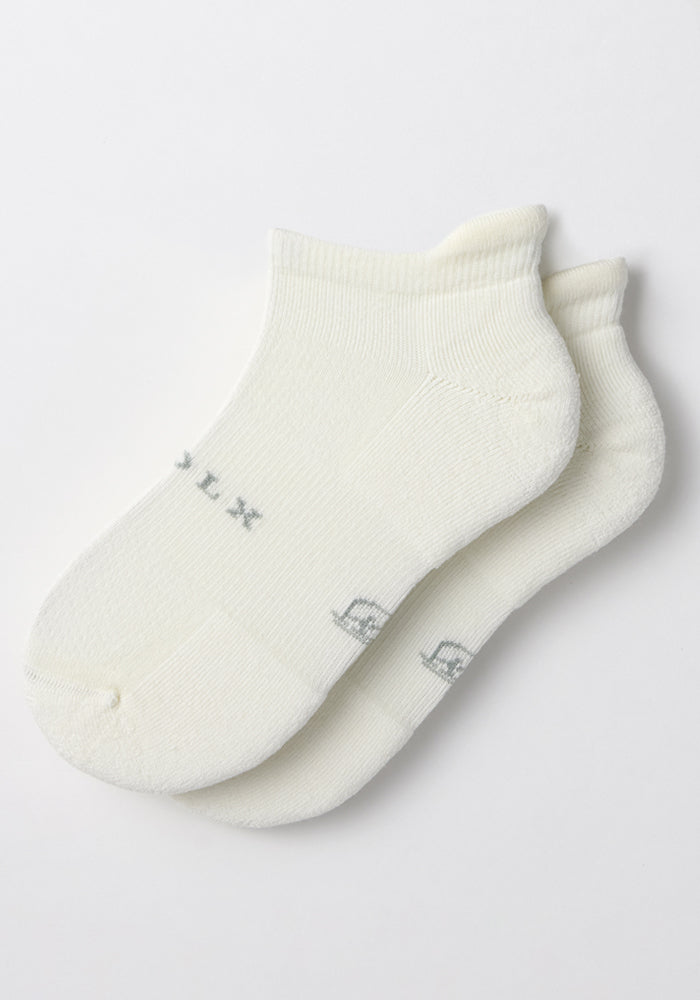 A pair of Woolx Mens Rowan No Show Socks in White Lightning with moisture-wicking fabric and subtle gray lettering by the toes, laid flat on a white surface.