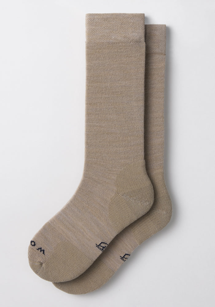 The Woolx Womens Chandler Mid Calf Sock in Simply Taupe is a light brown Merino wool dress sock with ribbed texture and small black text on the toe, offering odor resistance, style, and comfort for everyday wear.