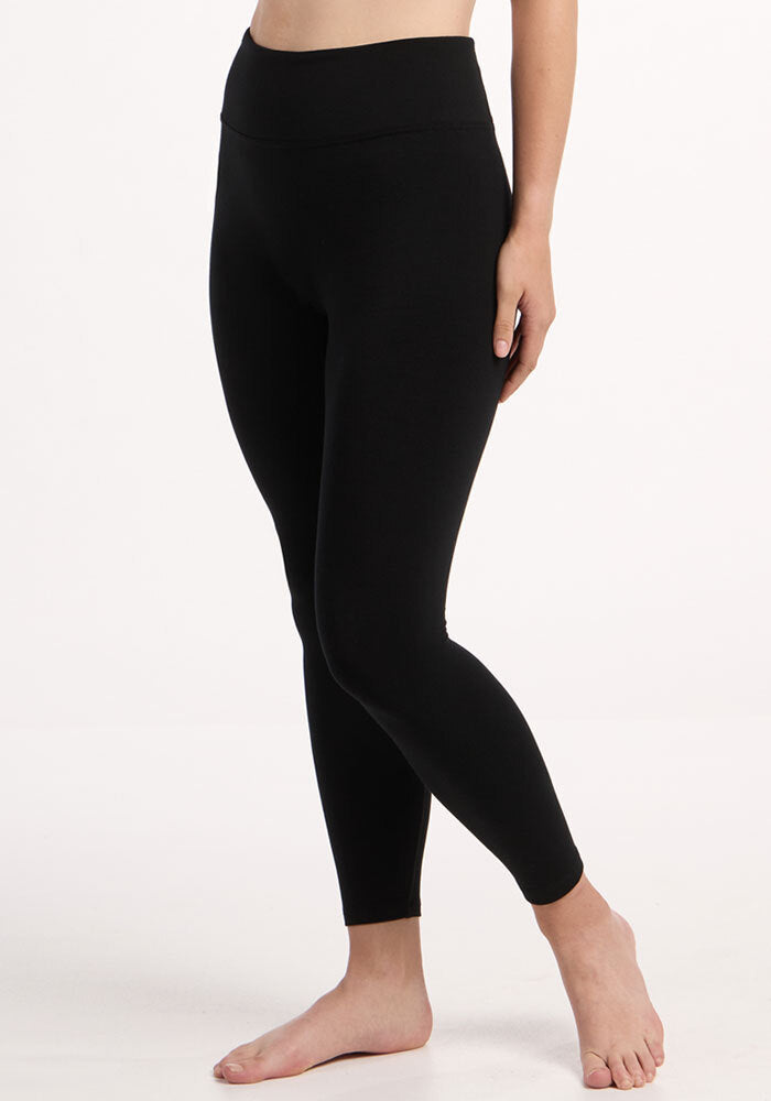 Model in Woolx Angela Leggings - Black, high-waisted, barefoot against a plain white background.