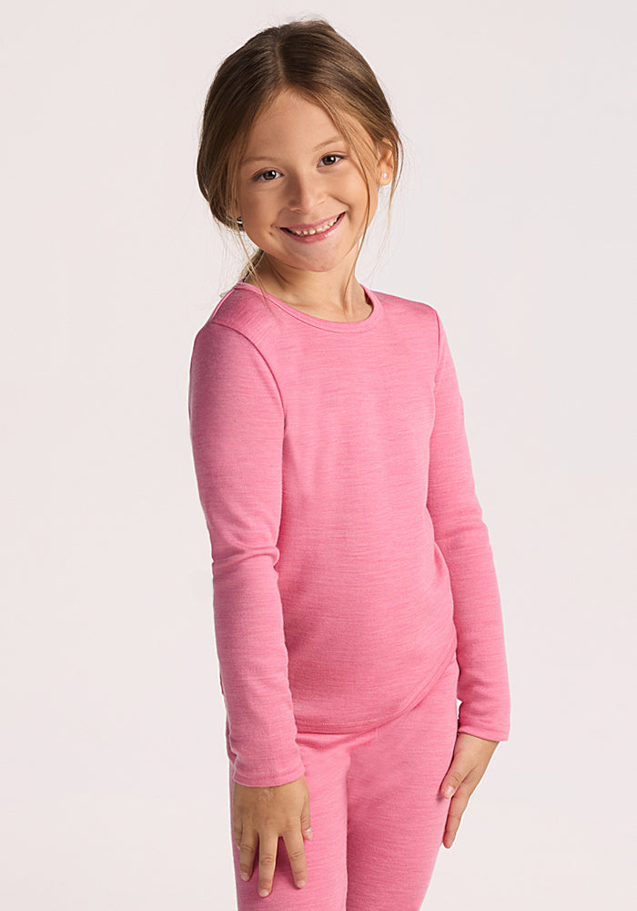 A young child with light brown hair smiles while wearing the Woolx Kids Explorer Base Layer Top - Pinky Promise, paired with matching pants, against a plain light background. 
