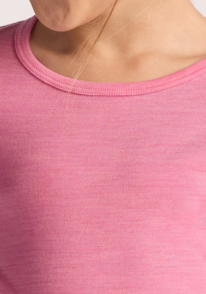 Close-up of a child wearing the Woolx Kids Explorer Base Layer Top in Pinky Promise, crafted from Australian Merino wool; neckline shows moisture-wicking fabric and a strand of light brown hair rests near the collar.
