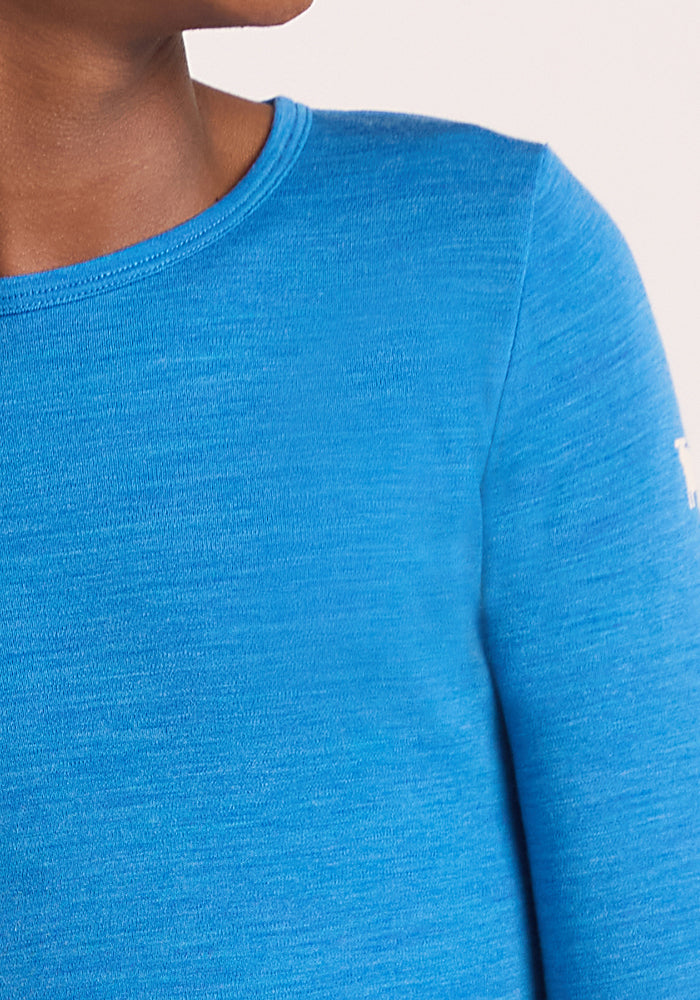 Close-up of a child wearing the Woolx Kids Explorer Base Layer Top in Blue Razz. Only the lower half of their face, neck, and shoulder are visible against a plain light background.