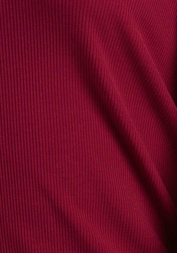 Close-up of Woolx Ainsley Sweater in Beet Red, highlighting the ribbed Merino wool texture and subtle folds.
