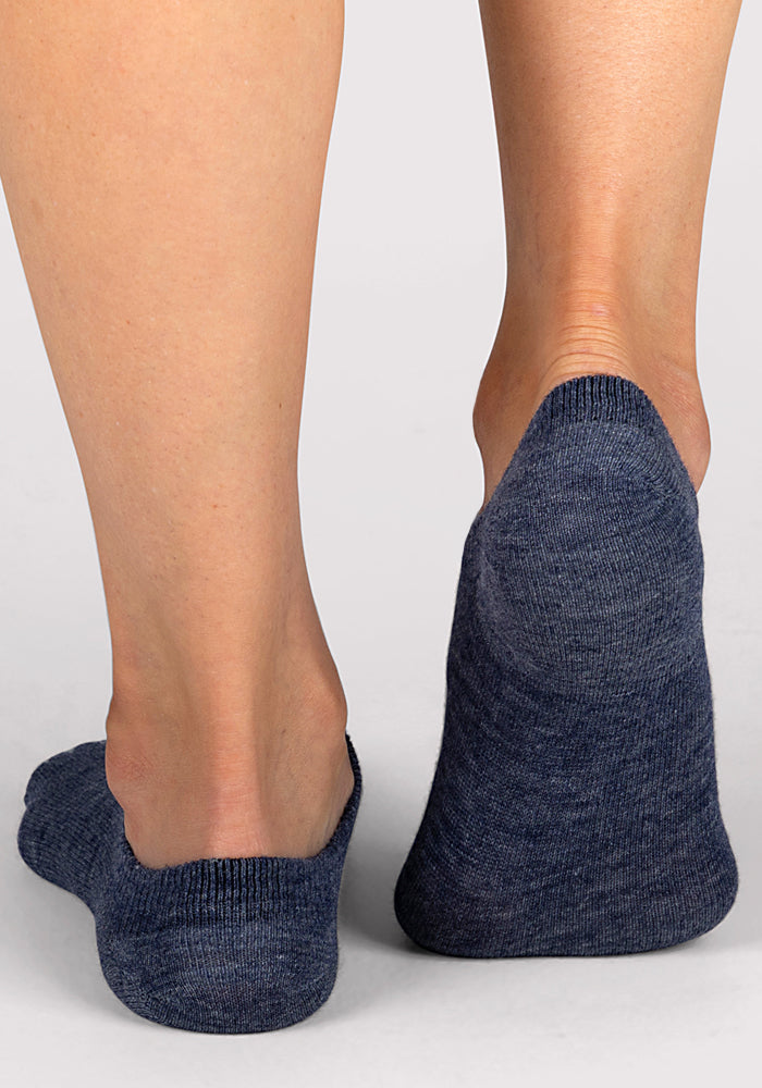 A close-up of two feet wearing Woolx Womens Daisy Ped Socks in Blue Jean Dream against a light gray background. These socks offer comfortable coverage without showing above the ankle.