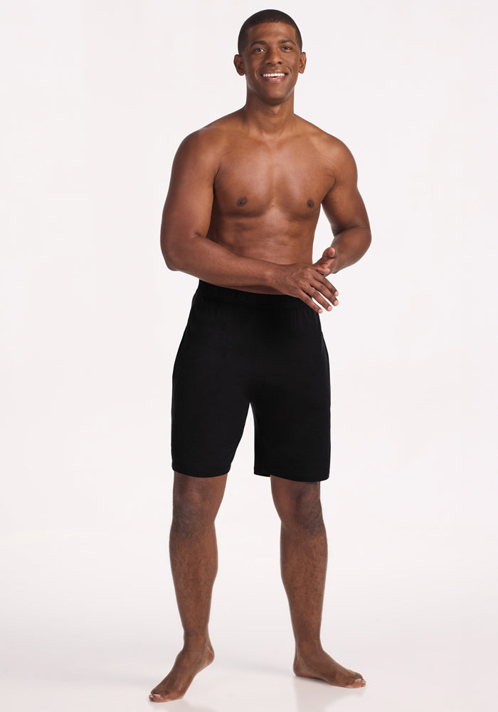Barefoot man poses in Woolx Archer Lounge Shorts - Black, against a white background, shirtless.