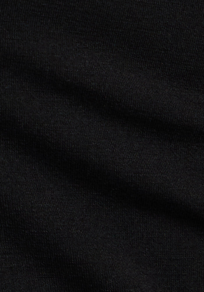 Close-up of the Woolx Audrey Tee in Black, featuring slightly ribbed merino wool fabric with gentle diagonal folds—perfect for a lightweight, relaxed fit.