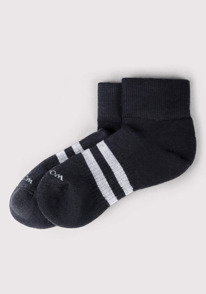 The Woolx Mens Rambler Ankle Sock in black features two white stripes near the top, crafted from Merino wool for superior moisture management, and is shown laid flat on a light gray background.