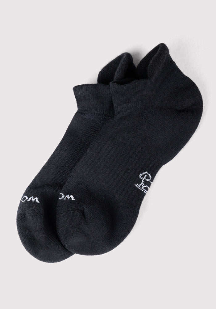 A pair of Mens Rowan No Show Socks by Woolx in black featuring small white designs near the toes, shown side by side on a light gray background.