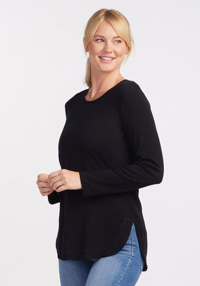 Woman in Woolx Blair Petite Tunic - Black and blue jeans stands against a plain white background, smiling.