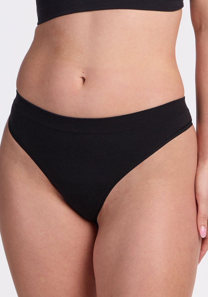 A person models the Woolx Farrah Thong in black, shown from midriff to upper thigh against a light background.