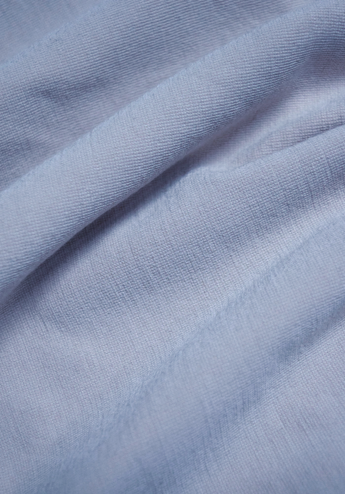 Close-up of the Woolx Hayden Bra in Bluebell, highlighting the light blue fabric's soft folds, smooth, slightly ribbed texture—ideal for a seamless comfort bra.