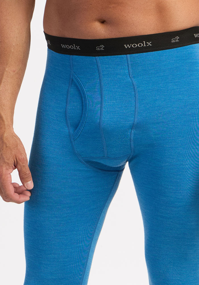 A person wears Woolx Backcountry Leggings in Blue Razz with a black “woolx” waistband, shown waist to mid-thigh.