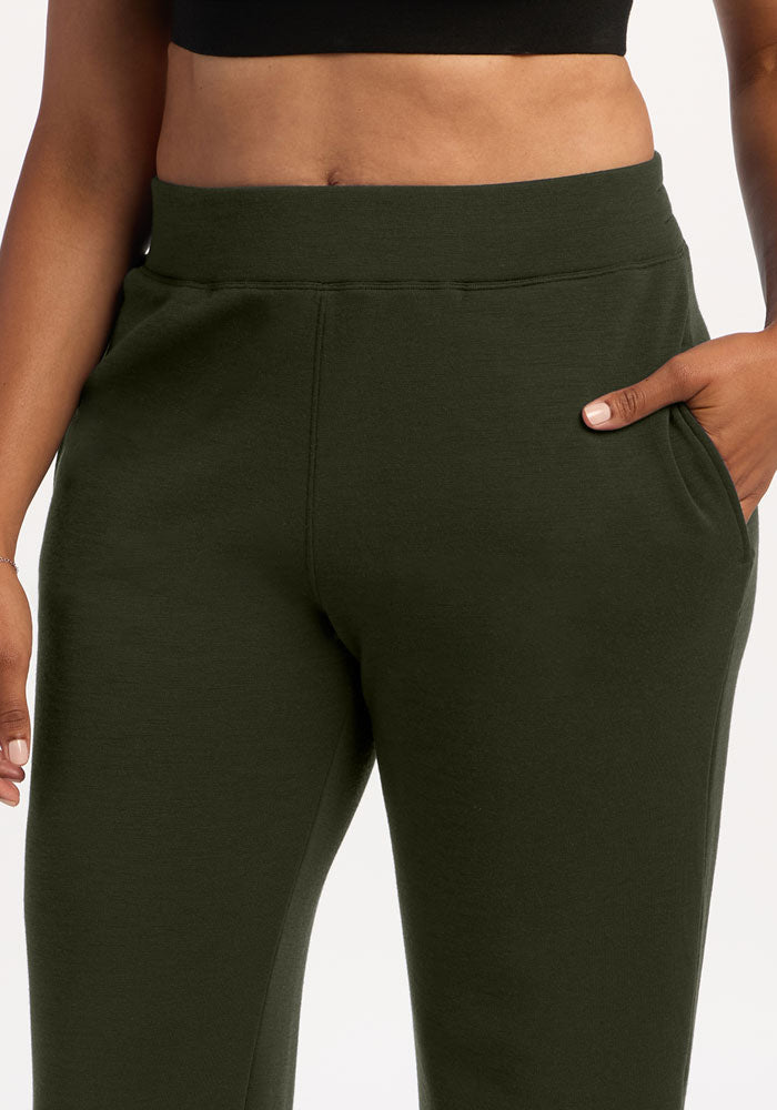 Model in Woolx Bree Lounge Pants - Duffel Bag, straight-leg fit, hand in pocket, black crop top, shown mid-torso down.