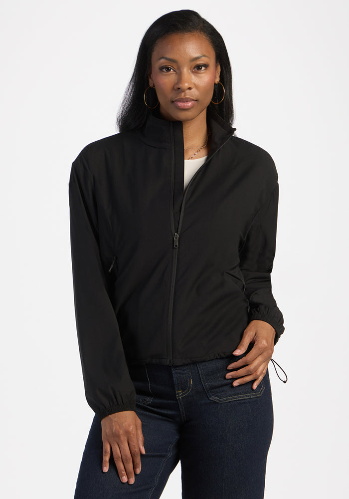 Woman in Woolx Cooper Windbreaker - Black and dark jeans, standing with one hand in her pocket. 