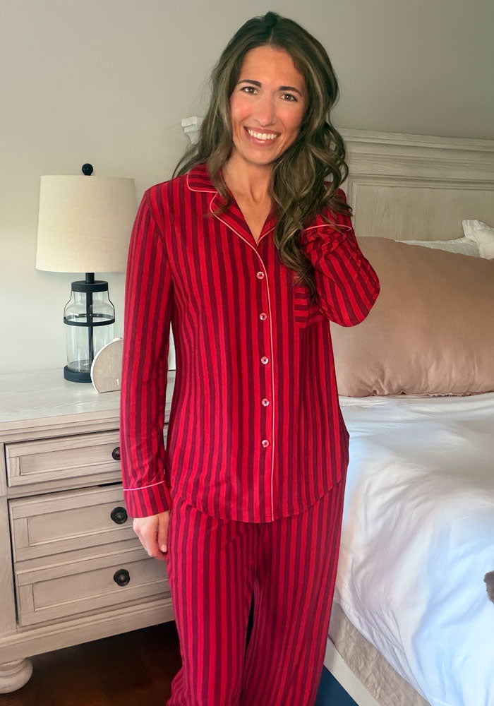 Woman wearing a Harper FeatherTouch® Pajama Set - Cherry Jam Stripe with long sleeves, red stripes, and white piping.
